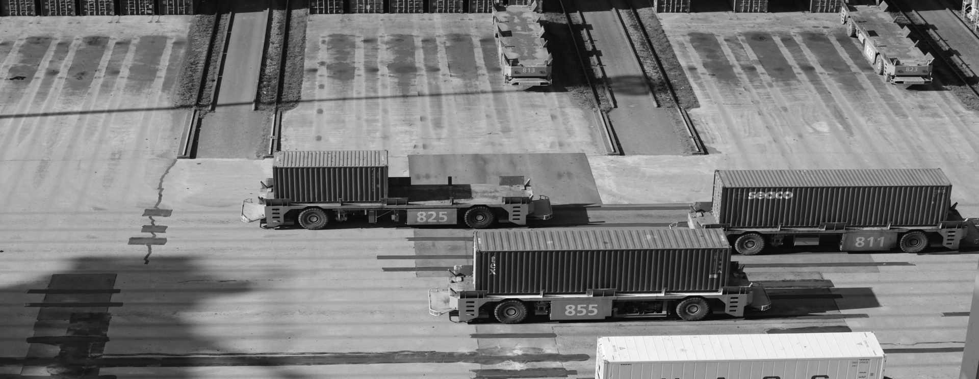 Trucks carrying containers across a terminal, seen from above